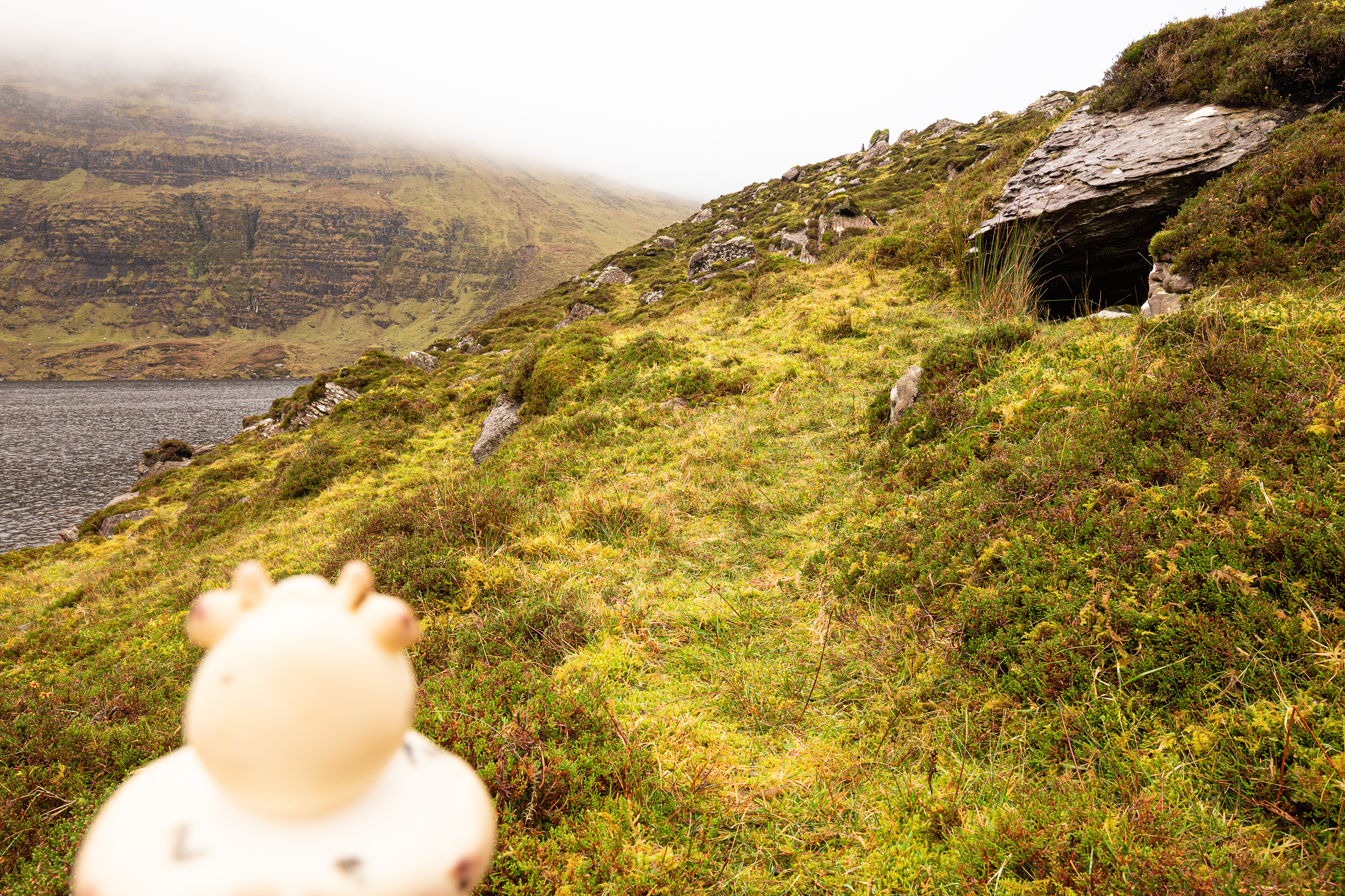 A photo of Bella the rubber duck in front of a foreboding natural underground tunnel, Glen of Aherlow, Tipperary Ireland.